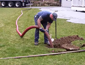 Septic pumping technician servicing a residential septic tank with a vacuum hose in Spokane, WA